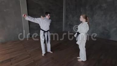 一个黑发男人和一个金发女孩正在健身房训练武术。 跆拳道学校的弹舞或单人决斗